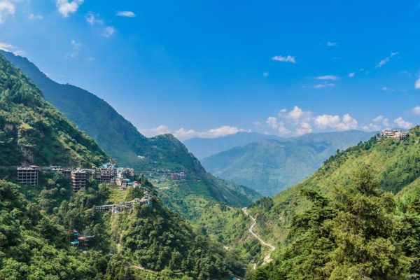 Breathtaking aerial view of lush green mountains and village in Rishikesh, India.