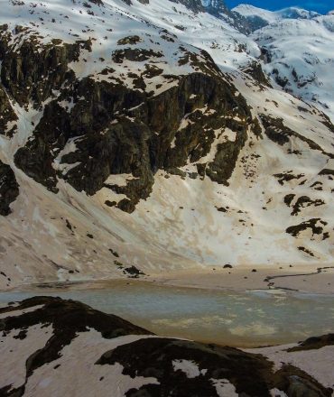 A breathtaking view of snowy mountains and a frozen lake in Occitanie, France.