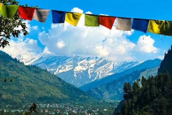 Charming view of Manali village with Himalayan mountains and colorful prayer flags in summer.
