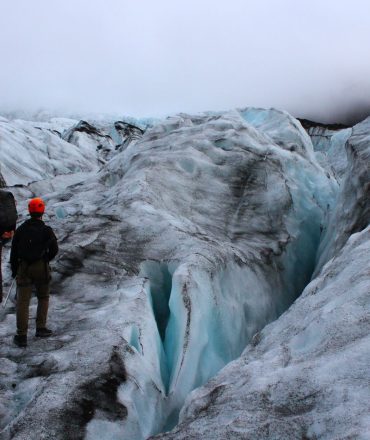Two adventurers explore a glacial landscape in Iceland, experiencing the raw beauty of nature.