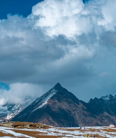 Snow-capped peaks of the Himalayas, partially sunlit, under dramatic clouds, perfect for winter travel adventures.