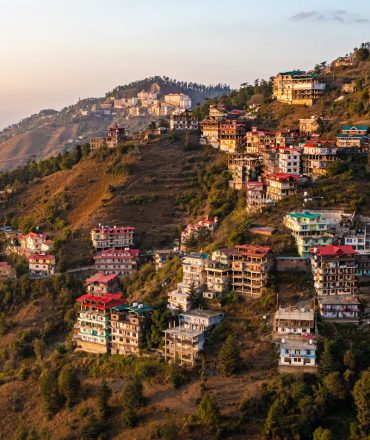 Aerial view of colorful buildings on Shimla hills during sunrise in Himachal Pradesh, India.