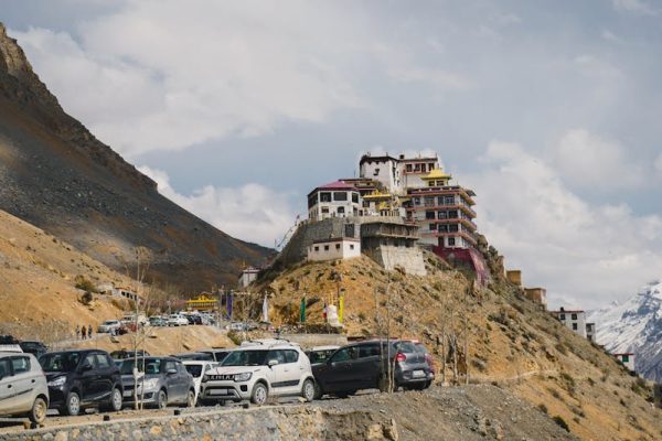 Picturesque view of Key Monastery atop a hill in Spiti Valley, with cars and mountains.