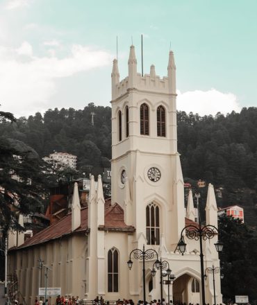 Gothic architecture of Christ Church in Shimla with a bustling crowd and scenic hills in the background.
