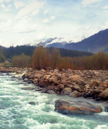 Beautiful mountain river flowing through a rocky valley with distant snowy peaks.